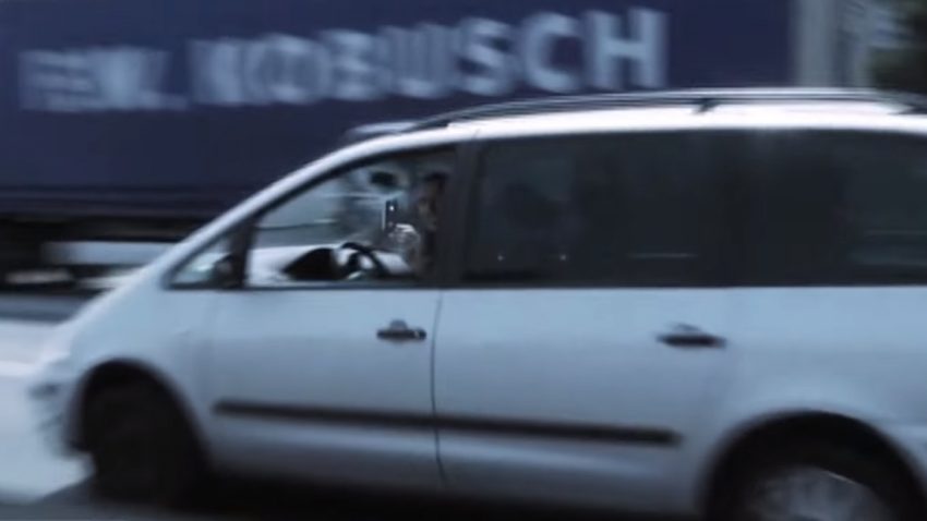 Ein Autofahrer filmt während der Fahrt mit einem Smartphone eine Unfallstelle.