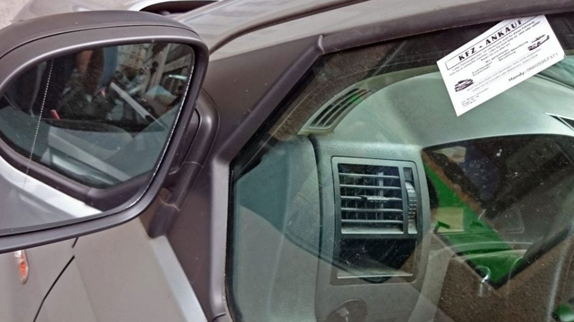 Eine Karte (Kfz-Ankauf) ist im Fenster eines Auto gesteckt.